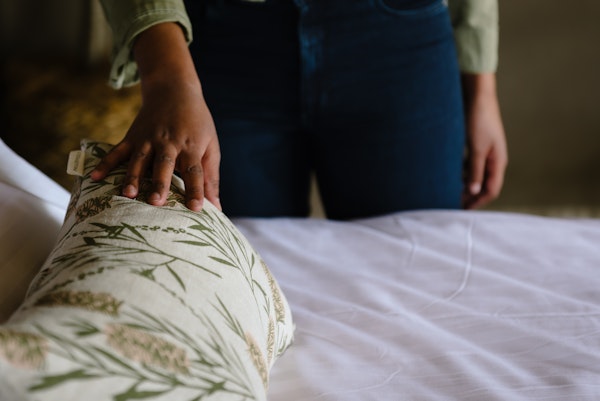 A woman stroking a floral cushion on a bed