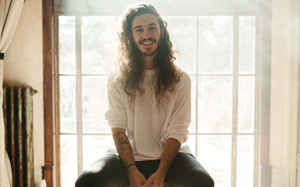 A man smiling into the camera with natural light behind