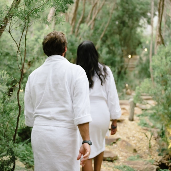 Two people walking through the Spa Dreaming Centre in white robes