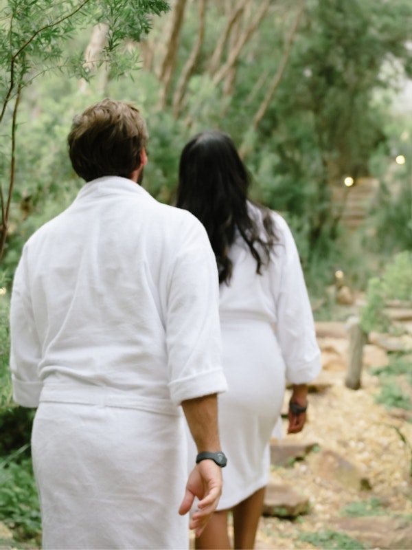 Two people walking through the Spa Dreaming Centre in white robes