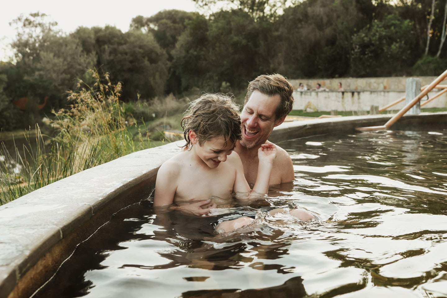 A dad and a child bathing in geothermal baths