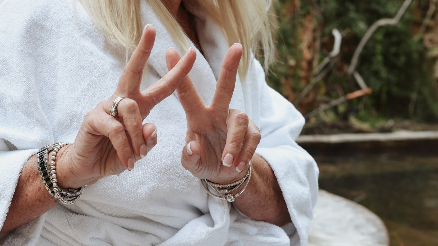 A woman doing two 'Peace' signs with her index fingers