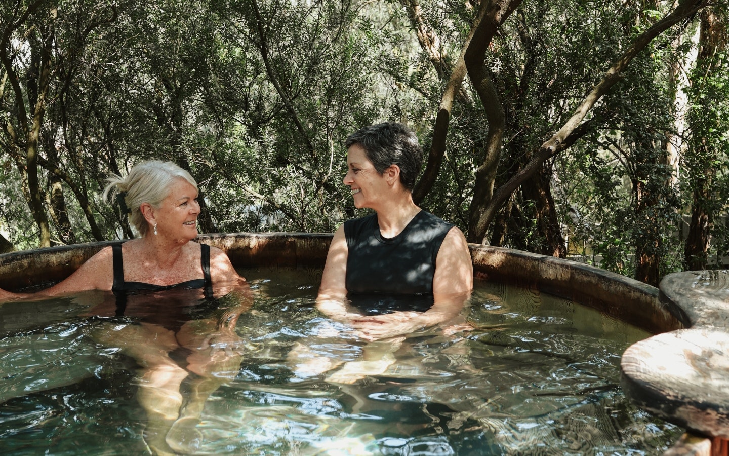 Two women in black bathers chatting in a geothermal pool
