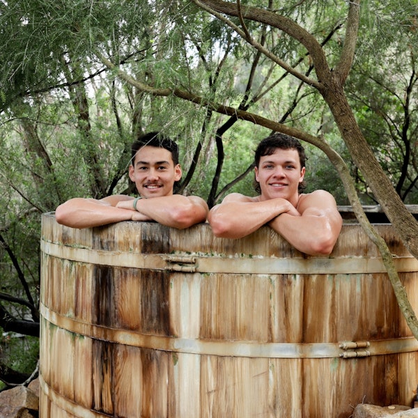 Two young men geothermal bathing in a large barrel