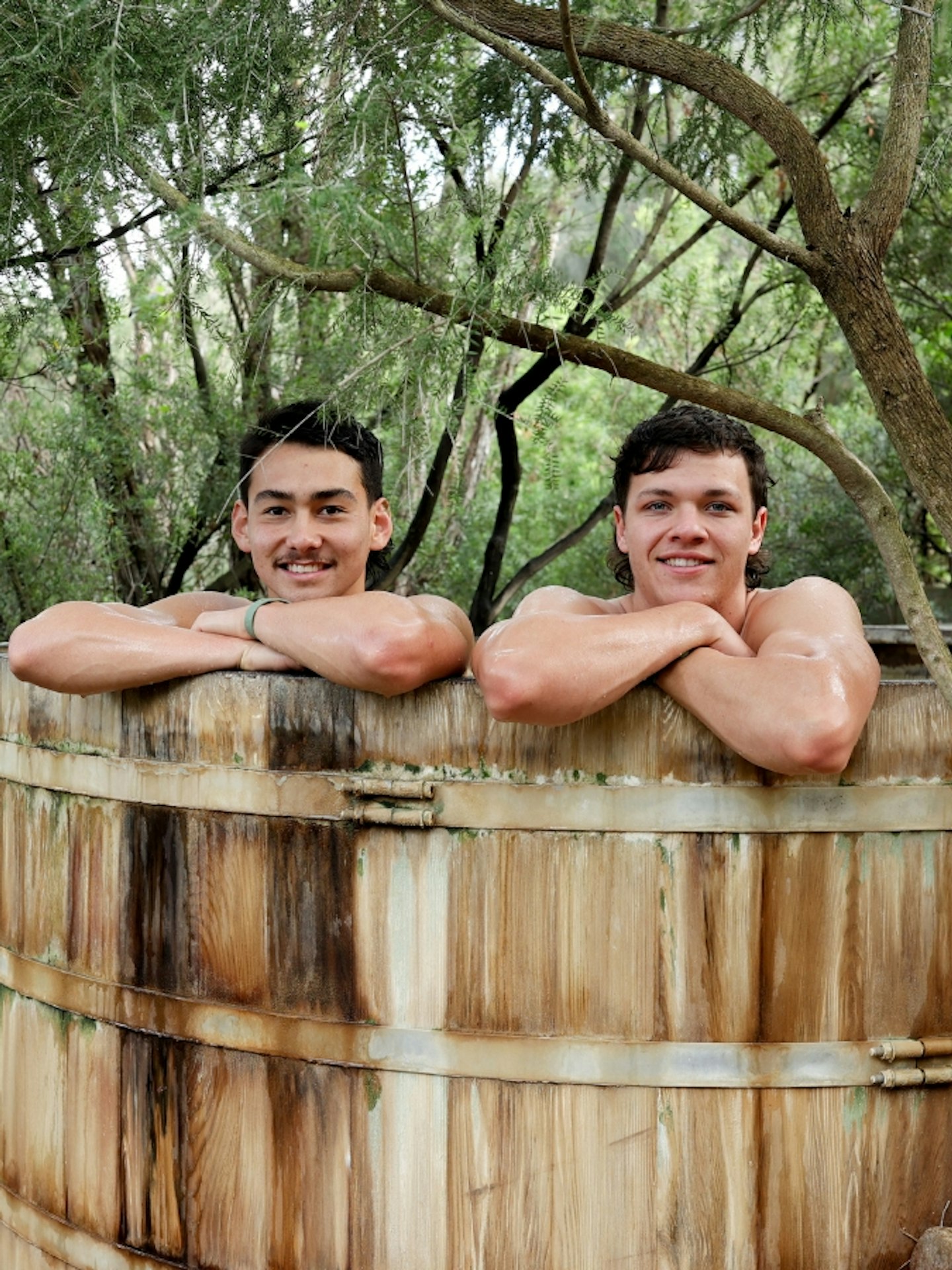Two young men geothermal bathing in a large barrel