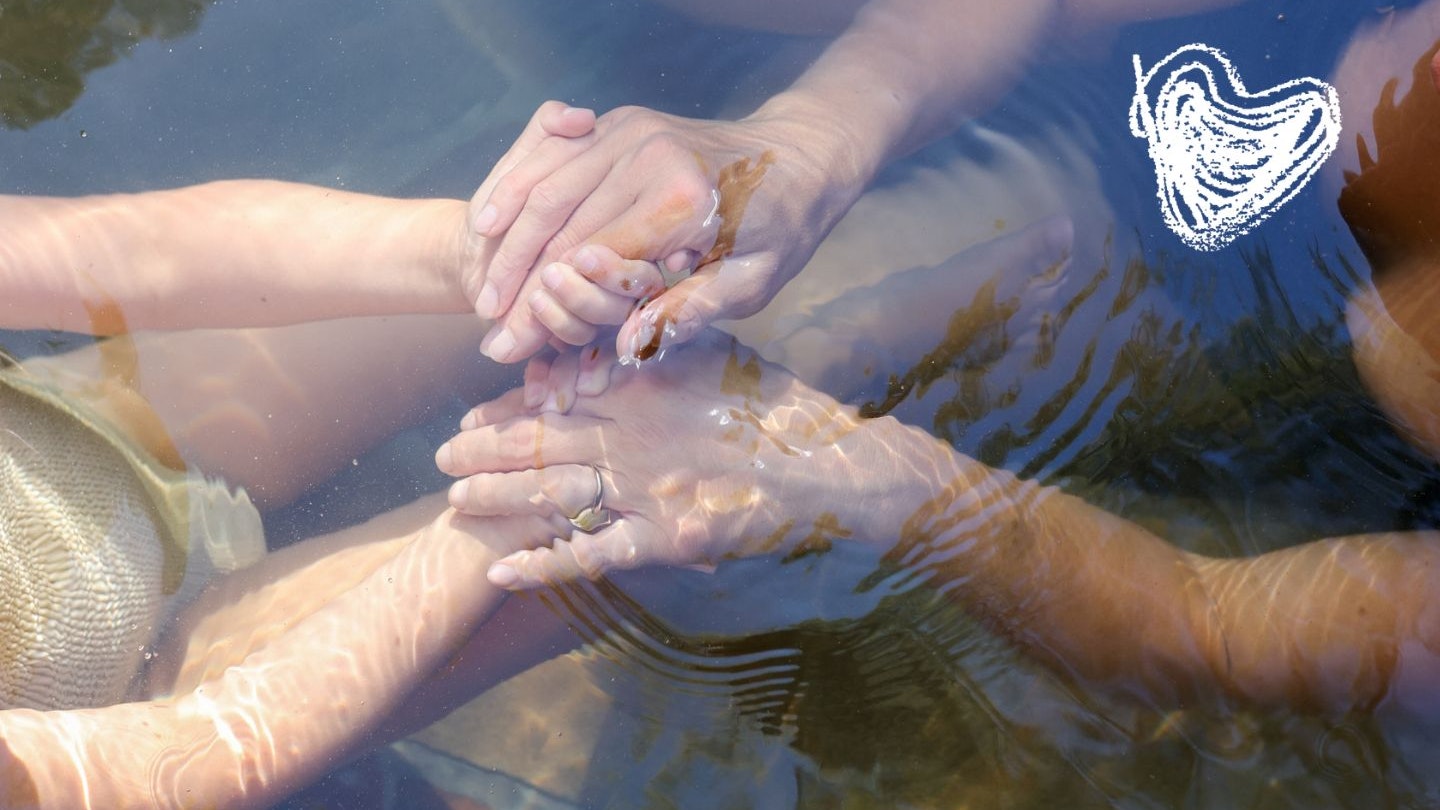 Mother and daughter holding hands under water