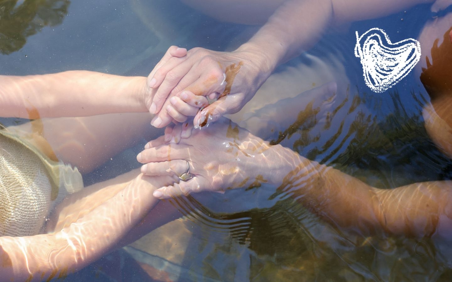 Mother and daughter holding hands under water