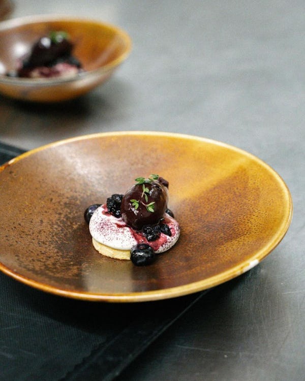 Kink Bar dessert on a golden plate with berries and mascarpone