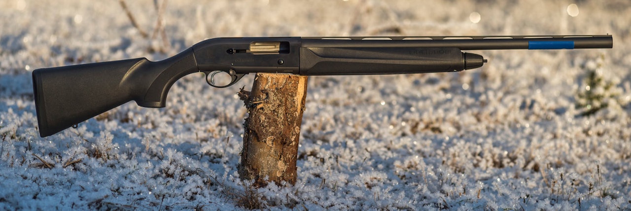 BERETTA HALVAUTOMAT HAGLE DAME: Kompakt halvauto med syntetstokk Beretta 300 Outlander 61 cm halvautomat hagle for damer sett fra siden liggende på en stubbe utendørs