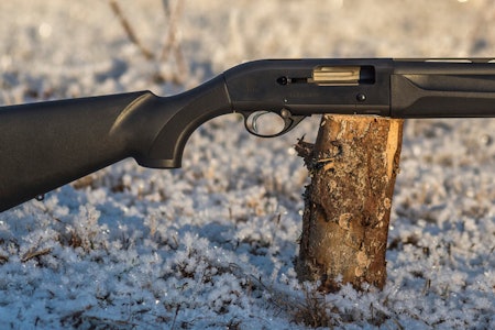 BERETTA HALVAUTOMAT HAGLE DAME: Kompakt halvauto med syntetstokk Beretta 300 Outlander 61 cm halvautomat hagle for damer sett fra siden liggende på en stubbe utendørs