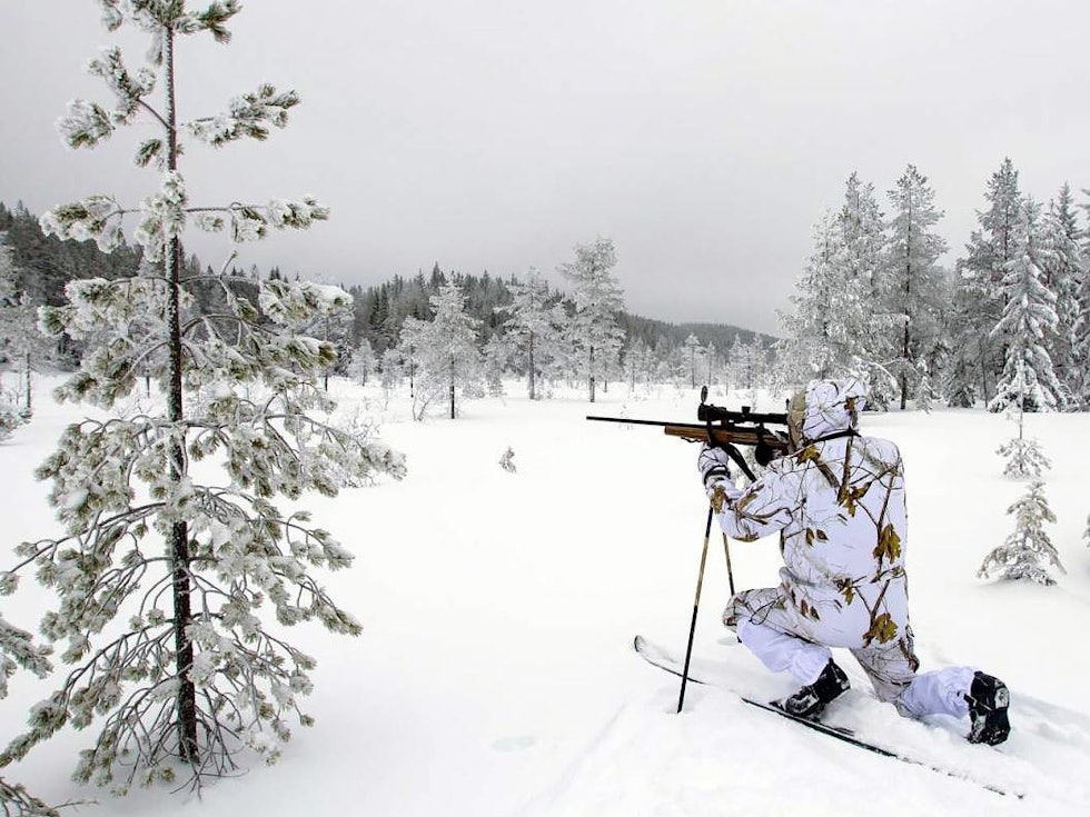 Jeger jakter på ski sikter med rifle i snøen