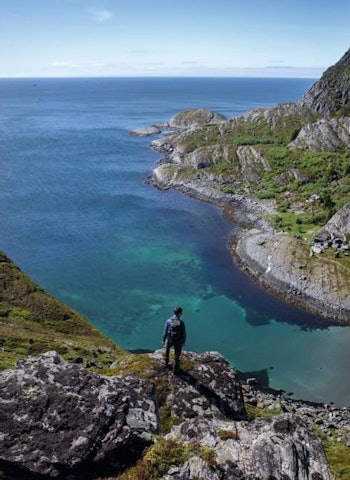 ØYHOPPING: Den tyske turisten Paul Grösch kikker ned på Nøvvika, helt sør på øya Lovund. Foto: Thomas Kleiven fjellturer på helgeland