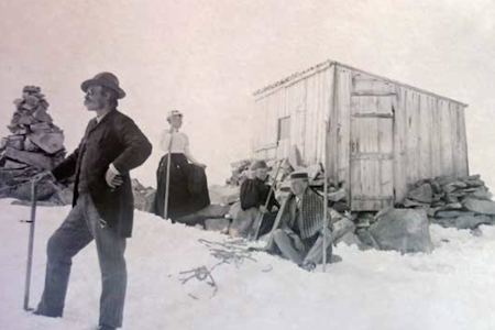 GALDHØPIGGEN JULI 1895: Legg merke til den beskjedne varden. Året etter ble den ble erstattet av en mye større. Eieren av den første Pigghytta, Knud «Stor-Knud» Vole, i forgrunnen. FOTO: Juvasshyttas samlinger  varden ved Galdhøpiggen