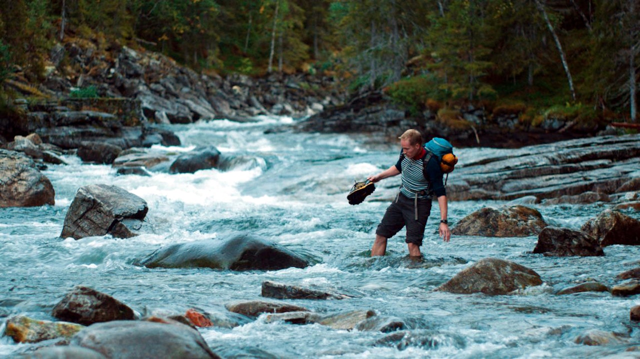 Ole Giæver er både regissør og hovedrolleinnehaver i filmen Mot naturen. Her krysser han en stri elv. Foto: Mer film fjellfilm filmer om friluftsliv