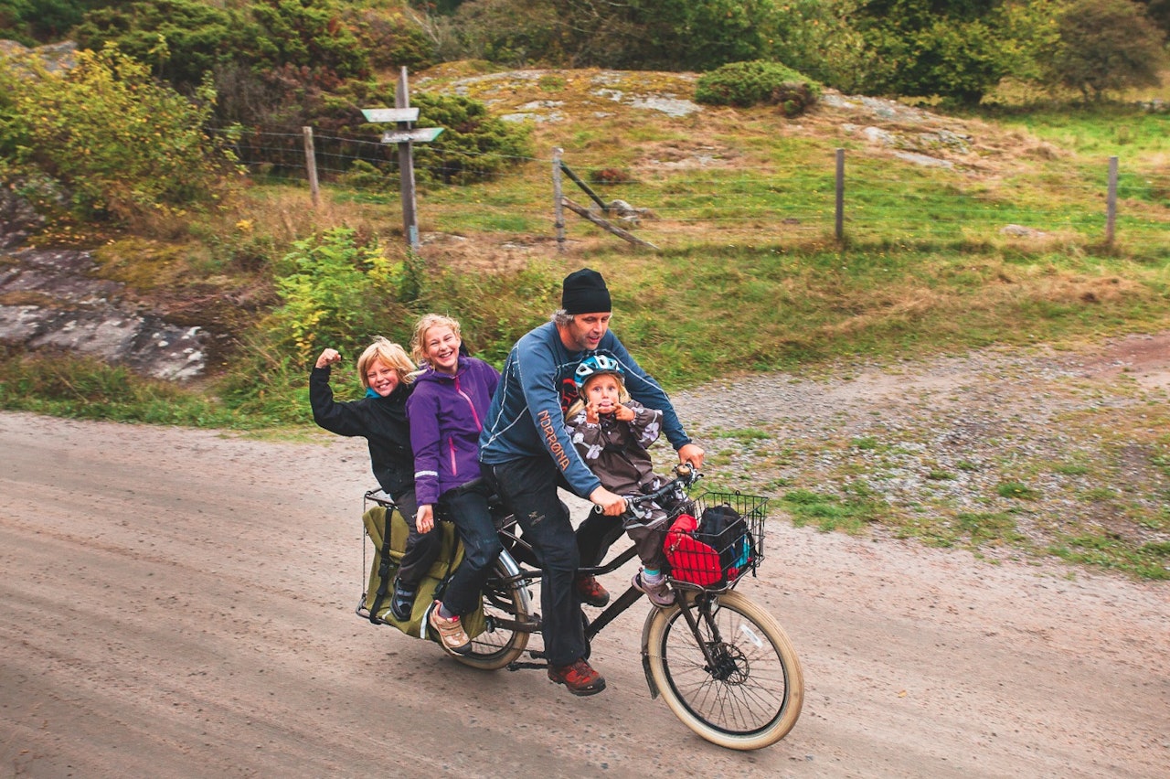BUDSJETTLØSNINGEN: Med en pris på like under ti tusen kroner er Trek Transport blant de rimeligste longtailsyklene på markedet. Dette var vår egen familiesykkel i halvannet år, før vi byttet til Surly Big Dummy med elmotor og enda mer lastekapasitet. Signe på tre år satt trygt og godt på eget barnesete rett bak styret, mens storesøsknene Eskil og Eiril hadde det like moro bakpå. Her på rolig kosetur langs bilfrie veier på Kosterøyene, med masse plass til bagasje i store sidevesker. Foto: Karoline Møller Den perfekte sykkel