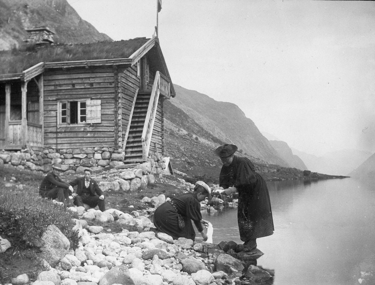 Kristine Bonnevie og Alette Falch (Schreiner) vasker klær ved Gjendebu sommeren 1896. De har vært på fottur sammen med Vilhelm Bjerknes (sittende til venstre) og Alfred Bryn (fotograf). Tilhører MUV, Universitetet i Oslo. 