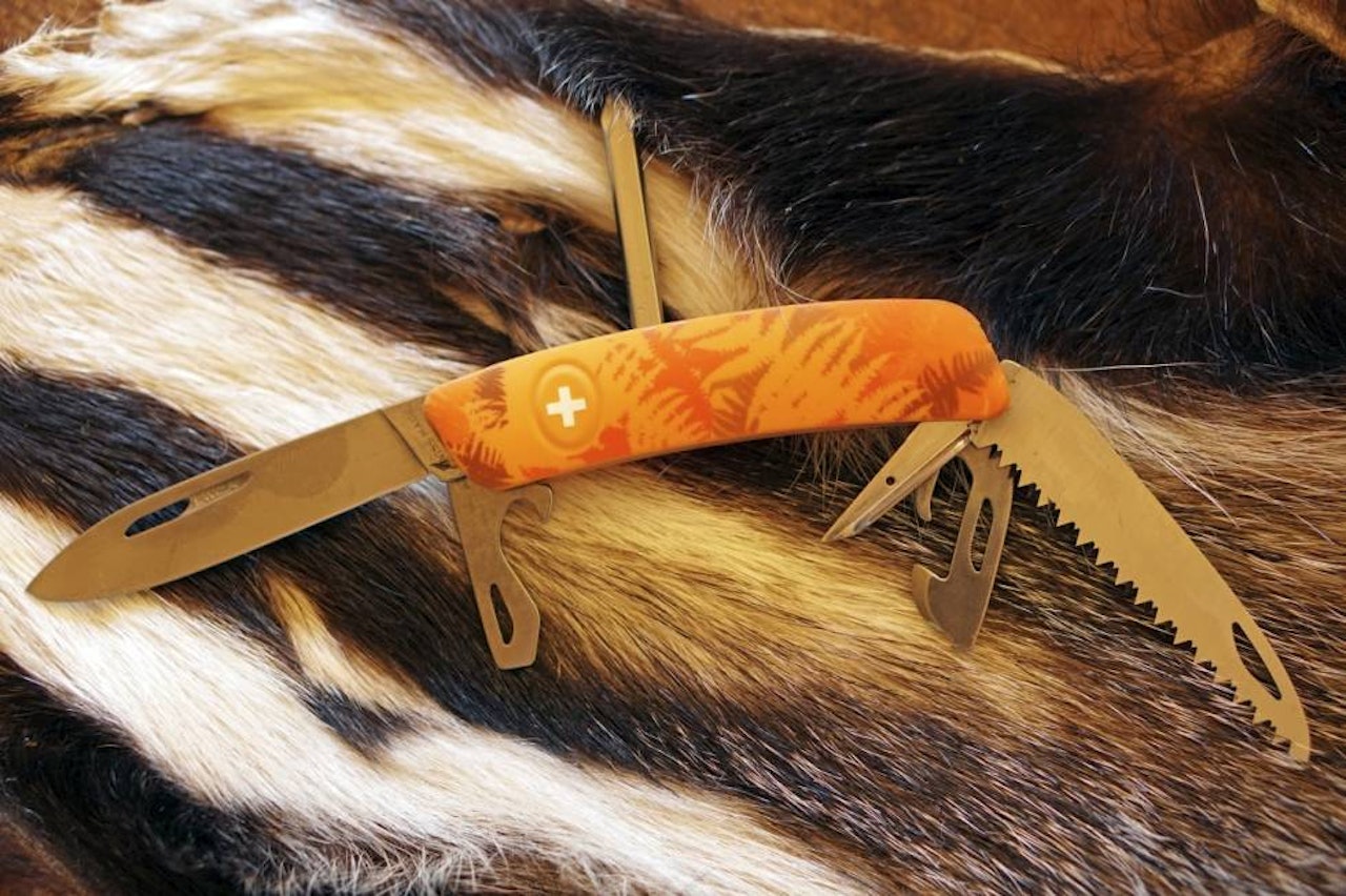 BLADLÅS: Swiza-kniven har både kniv, sag, boksåpner og flere skrutrekkere. Bladlås for kniven er logo-korset. BLADLÅS: Swiza-kniven har både kniv, sag, boksåpner og flere skrutrekkere. Bladlås for kniven er logo-korset.