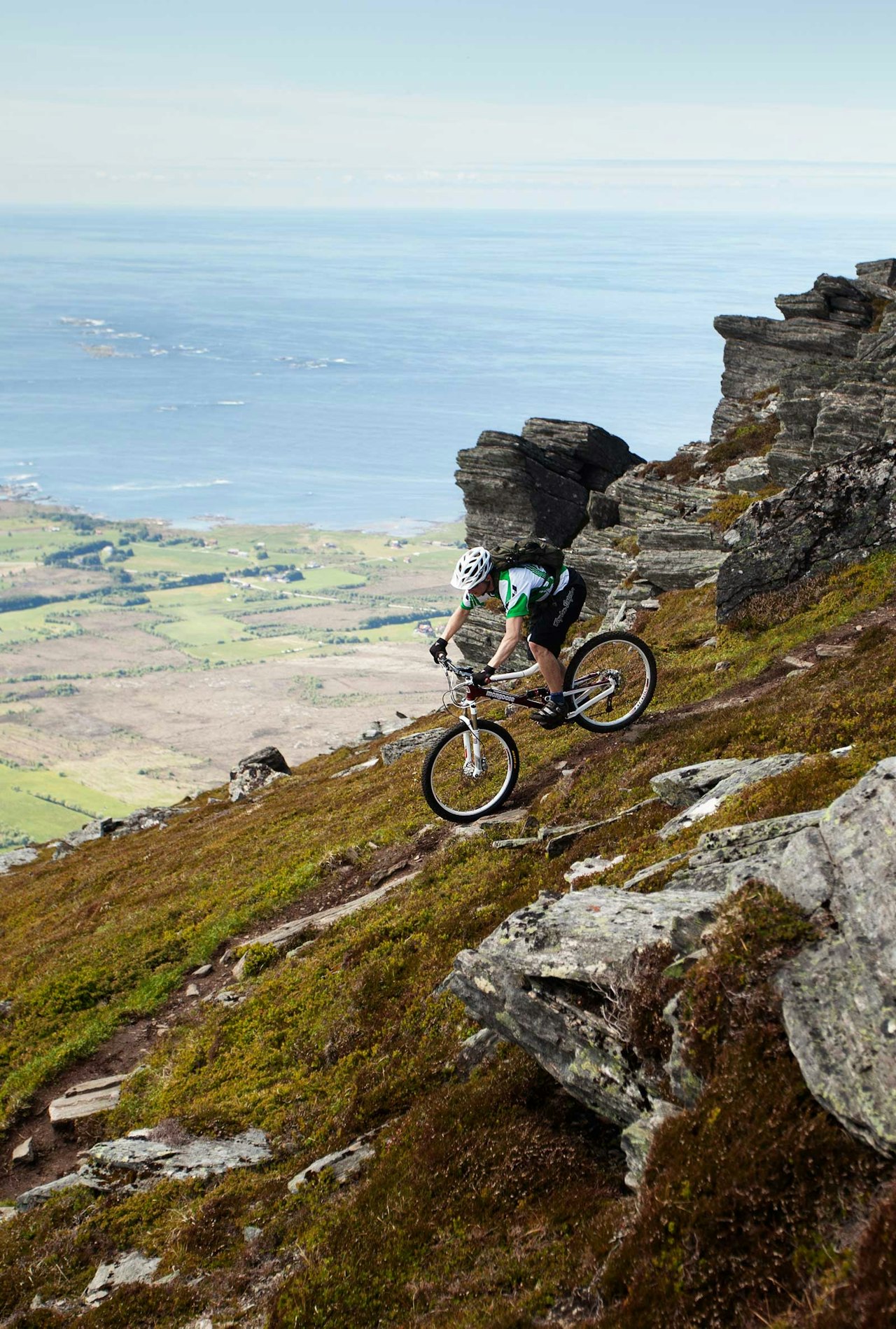 Mathias Marley sykler ned fra Sjurvarden med Hustadvika i bakgrunnen. / Stisykling i Norge. Mathias Marley sykler ned fra Sjurvarden med Hustadvika i bakgrunnen. / Stisykling i Norge.