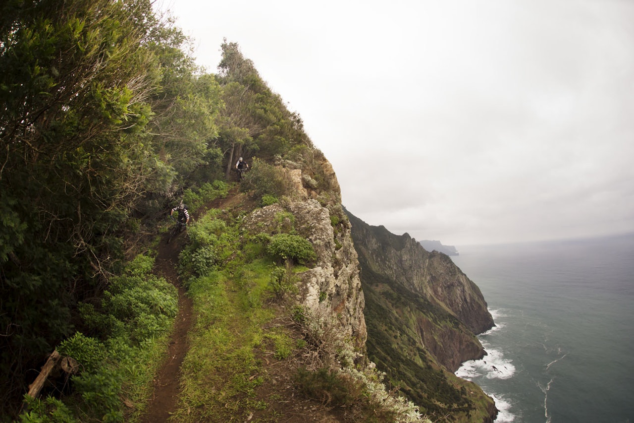PÅ KANTEN: Madeira er en opplevelse i seg selv, med eller uten sykkel. John Fernandes leder Knut Lønnqvist ned en sti langs et stup på nordsiden av øya. Med storslagen natur blir det hyppige stopp for å ta omgivelsene inn over seg. Foto: Kristoffer Kippernes