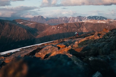 UJEVNT UNDERLAG: Men allikevel innenfor hva som kan sykles med et smil om munnen, med en liten margin. Kirsten Buck Rustad ruller ned fjellet mens solen legger seg lavt.  stisykling tromsø stromheimfjellet