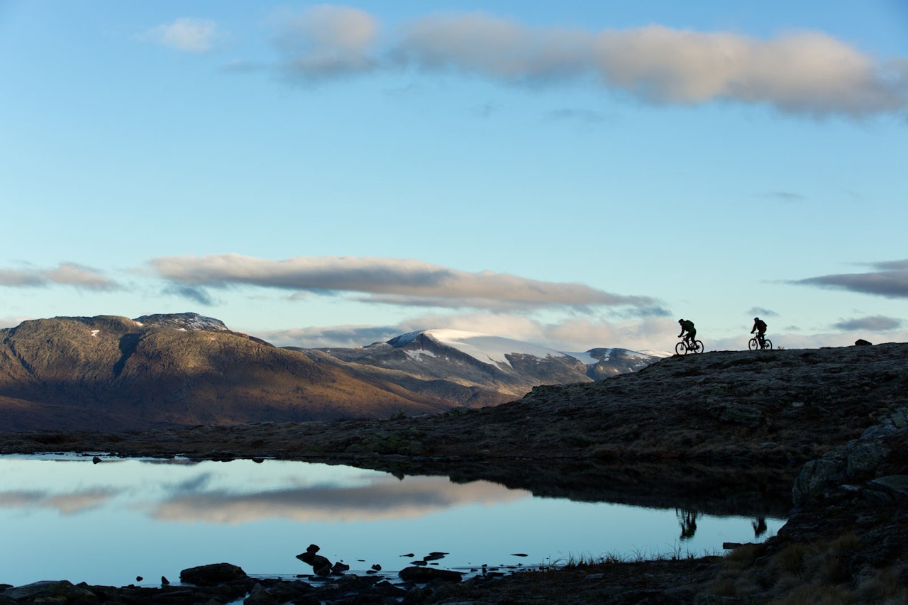 En tur over Molden er ekstra fint på en klarværsdag, hvor du kan se langt innover fjellene mot blant annet Hurrungane. Andreas Køhn og Knut Myking går i ett med landskapet. / Stisykling i Norge.
