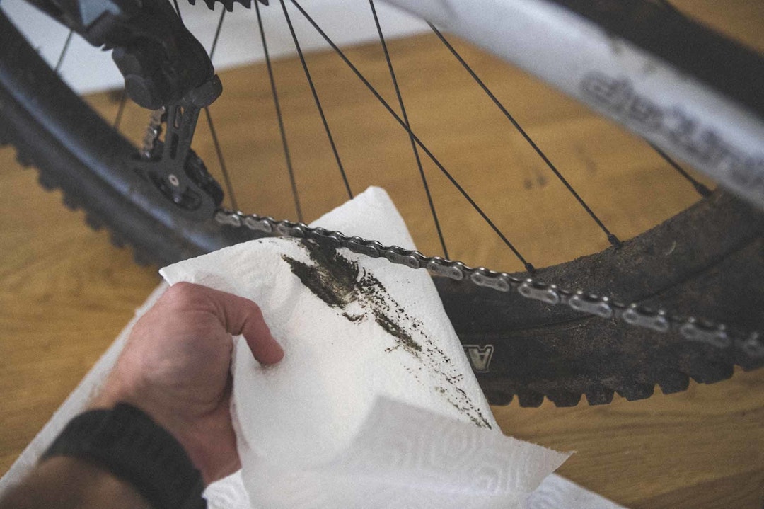 TØRK AV: Når du har dratt pedalene noen omdreininger, ta en fille eller tørkepapir, og hold under og rundt kjedet mens du fortsetter å dra kjedet rundt. Målet er å få tørket av det overflødige smøremiddelet. smøre kjedet sykkel