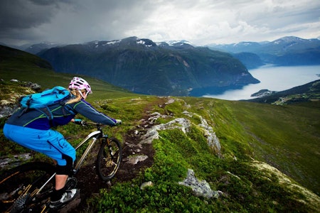 Ned fra Mefjellet byttes etterhvert fjordutsikt ut mot tett skog. Like bratt er det dog. / Stisykling i Norge. Ned fra Mefjellet byttes etterhvert fjordutsikt ut mot tett skog. Like bratt er det dog. / Stisykling i Norge.