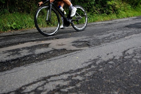 Syklist med karbonhjul og hull i asfalten