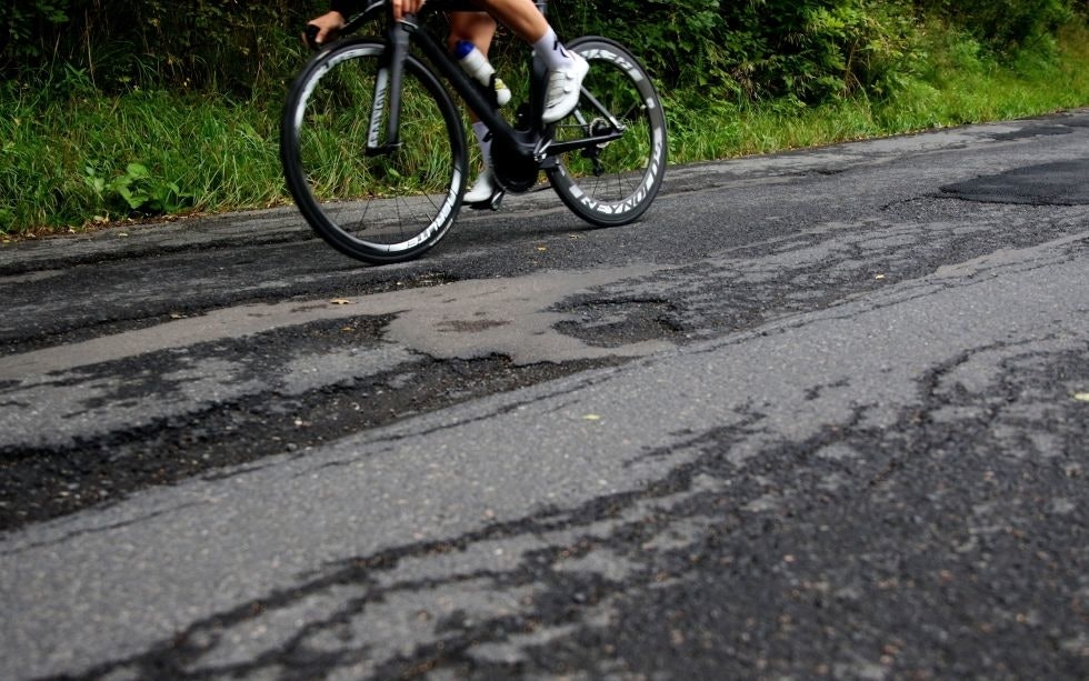 Syklist med karbonhjul og hull i asfalten