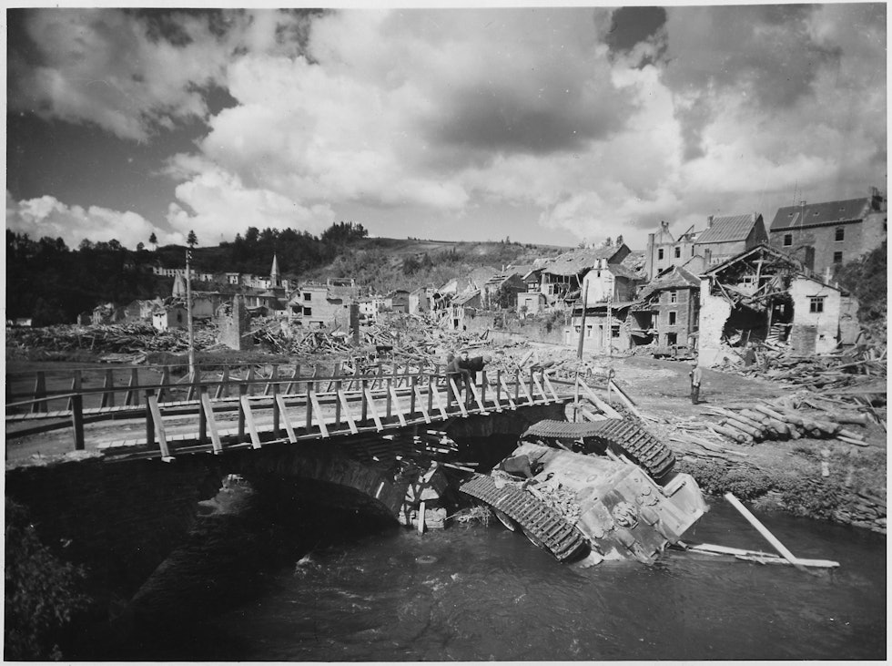 An_overturned_German_tank_lies_in_a_shallow_stream_alongside_a_rebuilt_bridge_in_war-ravaged_Houffalizo,_Belgium._-_NARA_-_196224