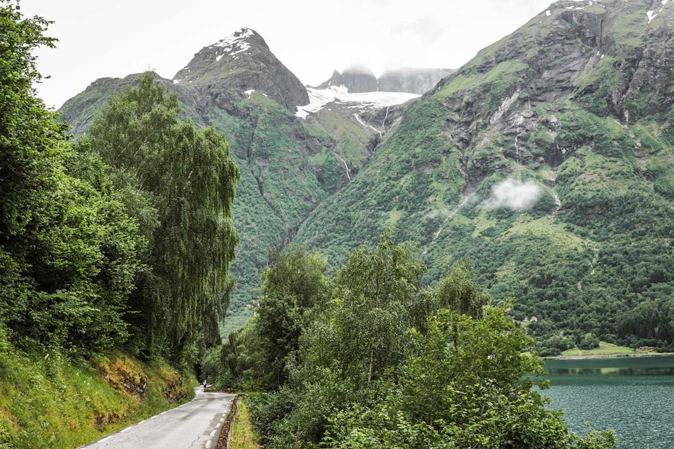 FRODIG: Den hvitstiplede veien forbi Hjelle er en verdig avslutning på turen over fjellet. Hovedveien går i tunell, den gamle veien i en slynge langs Opstrynsvatnet. FRODIG: Den hvitstiplede veien forbi Hjelle er en verdig avslutning på turen over fjellet. Hovedveien går i tunell, den gamle veien i en slynge langs Opstrynsvatnet.
