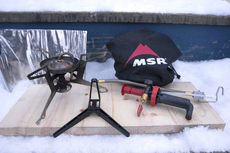 MSR Whisperlight Universal multifuelbrenner med brennerhode, pumpe og pakkpose på fjøl i snøen