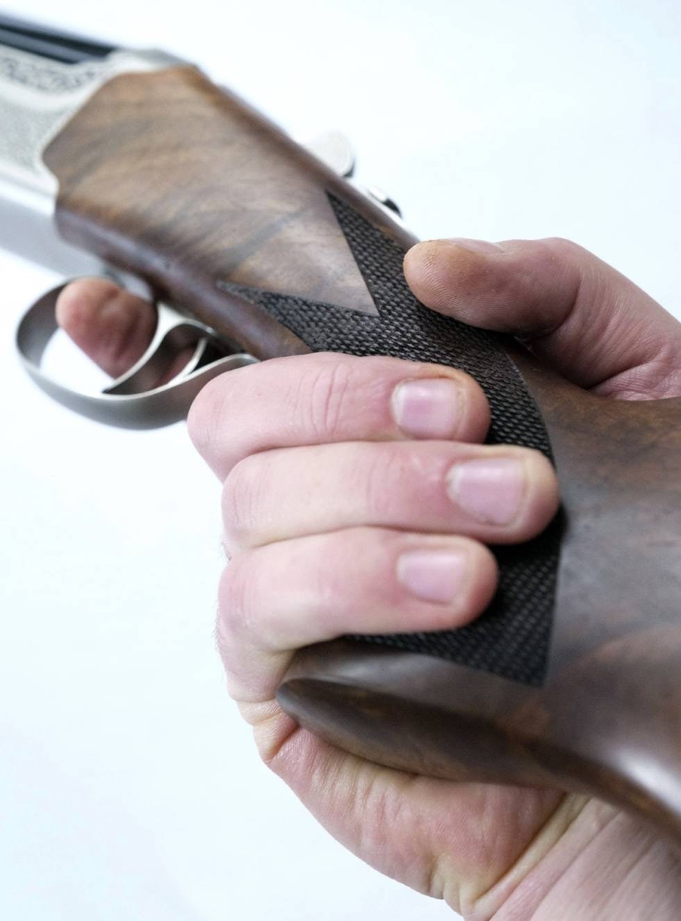 Nærbilde av hånd på pistolgrepet til haglen Khan K500 Lux valnøtt