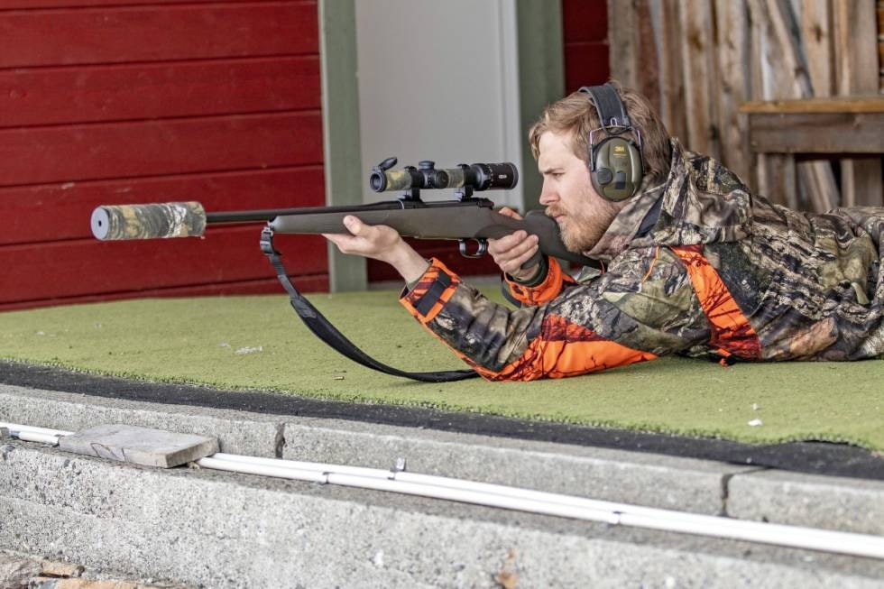 Jeger i liggende jegerstilling sett fra siden sikter med rifle og skytestropp