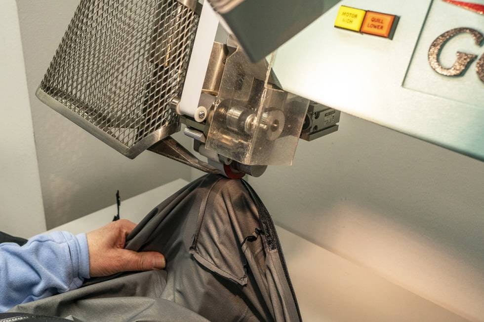 3 – Sømmer teipes: Ei spesialmaskin fra Gore bruker varmluft på 500 grader for å sveise fast teipen som tetter sømmene. 3 – Sømmer teipes: Ei spesialmaskin fra Gore bruker varmluft på 500 grader for å sveise fast teipen som tetter sømmene.