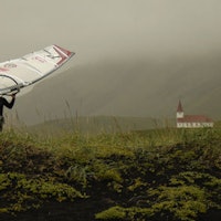 SURF OG KATEDRAL: Profesjonell windsurfer Vidar Jensen går med arbeidsantrekk og verktøy. Ved Vik på sørspissen av Island. Foto: Reinhard Müller