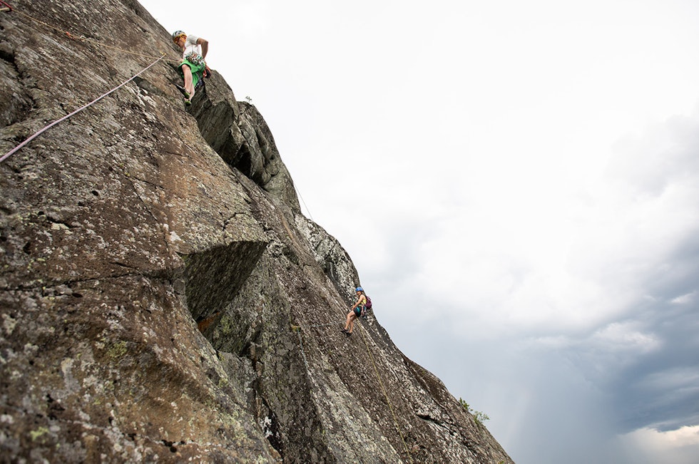 MYE SOM SKJER: Joakim i aksjon på Lyneggen med ei dame rappellerende i bakgrunnen og tordenskrall i lufta. Foto: Tore Meirik Joakim Eide Størenhammeren klatring