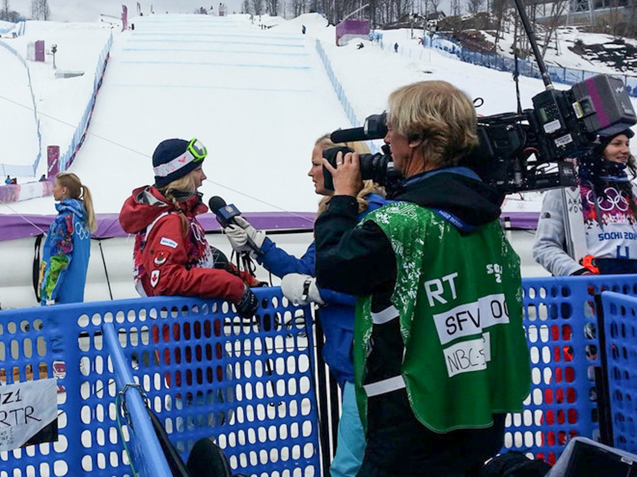 BEST I KVALIKEN: Dara Howell, som her intervjues av amerikansk TV med slopestyleløypa i bakgrunnen, vant dagens kvalik i historiens første OL-konkurranse i ski slopestyle. Foto FIS