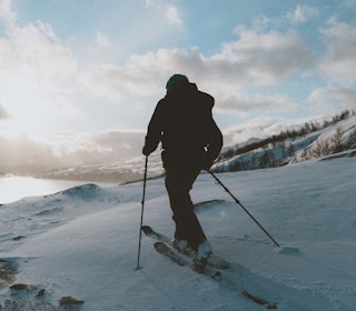 Snart kan folk suse forbi deg i fjellheimen på Elski. Foto: Kristoffer Kippernes En mann på ski går mot sola i et kupert landskap