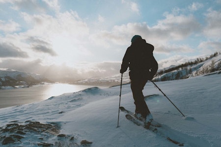 Snart kan folk suse forbi deg i fjellheimen på Elski. Foto: Kristoffer Kippernes En mann på ski går mot sola i et kupert landskap