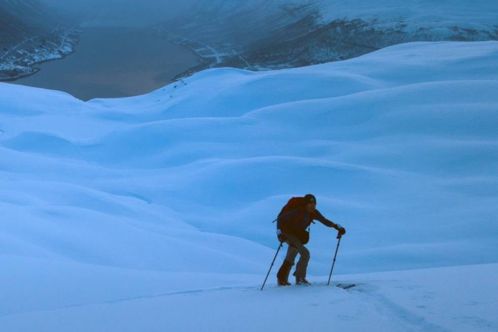 SIKRESTE VEI: Espen Nordahl tråkker spor i nysnø på vei mot Tromsdalstinden. I bakgrunnen skimtes Sørbotn innerst i Ramfjorden. Bildet er noe fargejustert. Foto: Erlend Sande