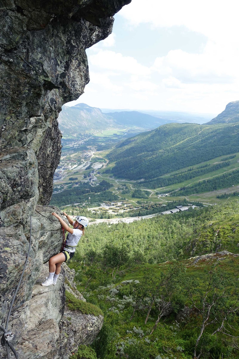 LUFTIG: Maria Wassdahl Meirik holder seg fast i fjellet med jernstigen høyt over skisenteret i Hemsedal. Sentrum ses i bakgrunnen. Bilde: Tore Meirik Hemsedal-via-ferrata