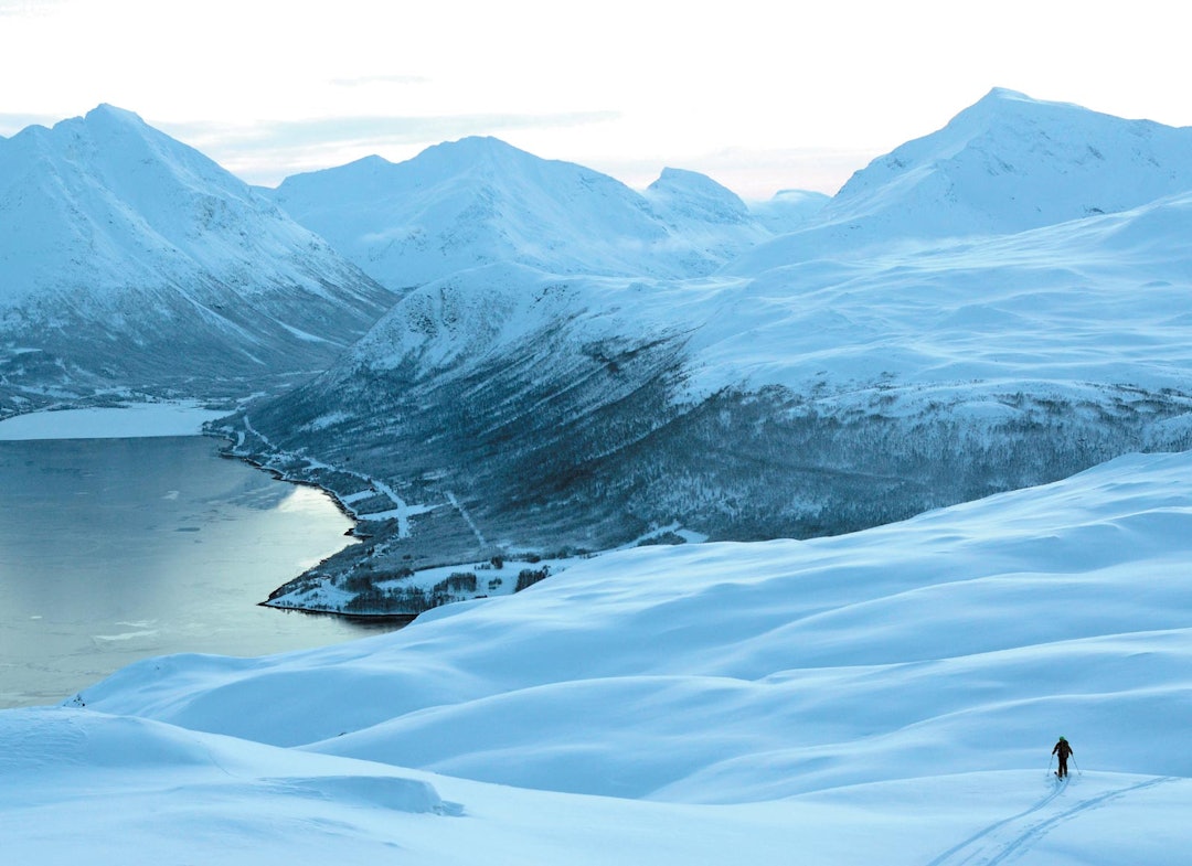 Svein Mortensen nyter kulden og et magisk lys på baksiden av Tromsdalstinden med utsikt mot Ramfjorden. Foto: Espen Nordahl. / Toppturer i Troms.