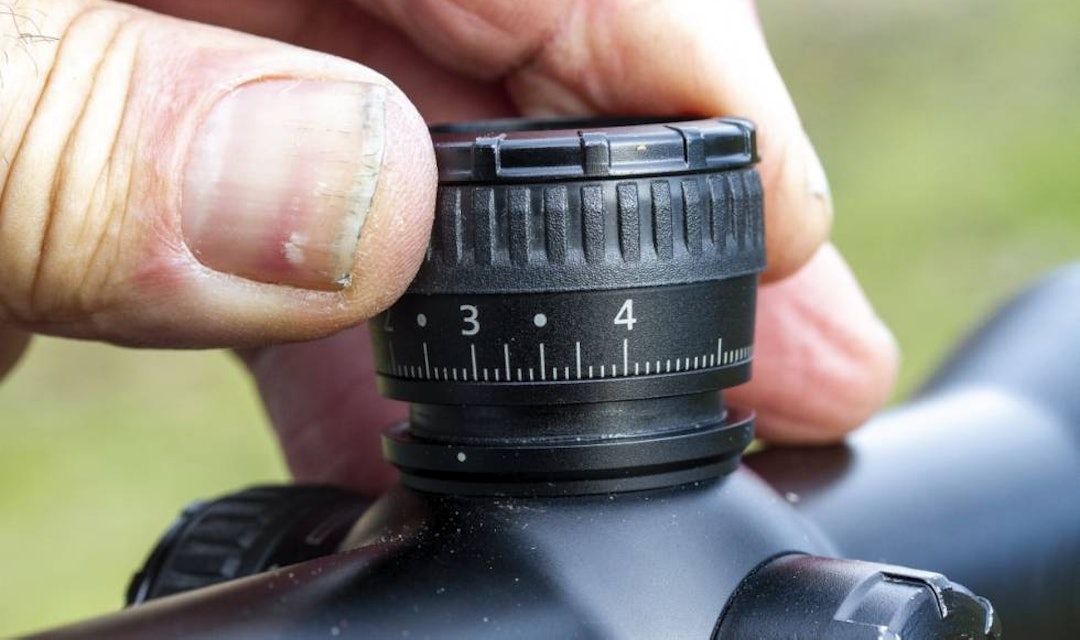 Guide: Er du nervøs for å skru for mye på kikkertsiktet? Finn nyttige tips i vår guide for å skyte inn en riflekikkert. En hånd som vrir på justeringstårnet til en riflekikkert for å skyte inn kikkertsiktet.