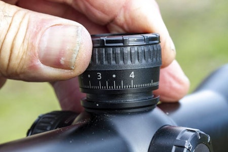 Guide: Er du nervøs for å skru for mye på kikkertsiktet? Finn nyttige tips i vår guide for å skyte inn en riflekikkert. En hånd som vrir på justeringstårnet til en riflekikkert for å skyte inn kikkertsiktet.