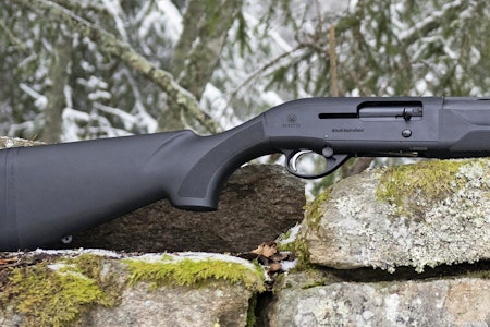 Beretta A300 Outlander Synt er en stilren og tradisjonell halvautomat hagle. Halvautomat hagle Beretta A300 Outlander Synt sett fra siden liggende på en stein utendørs