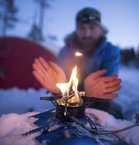 OPPVARMING: Å ta i primusen kan være svært kaldt en vinterdag, men når flammene brer seg får man varmen i fingrene igjen. Foto: Randulf Valle