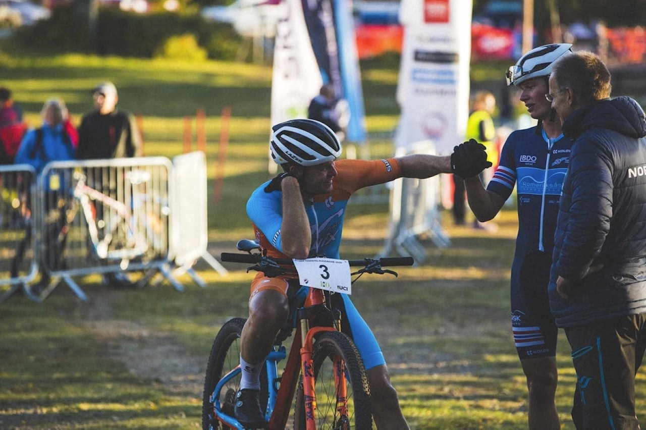 LANDSLAG: Emil Hasund Eid (t.v.) gir Knut Røhme en knoke, sammen med landslagssjef Eddy Knudsen Storsæter. Foto: Kristoffer H. Kippernes.  landslag terrengsykling rundbane 2022