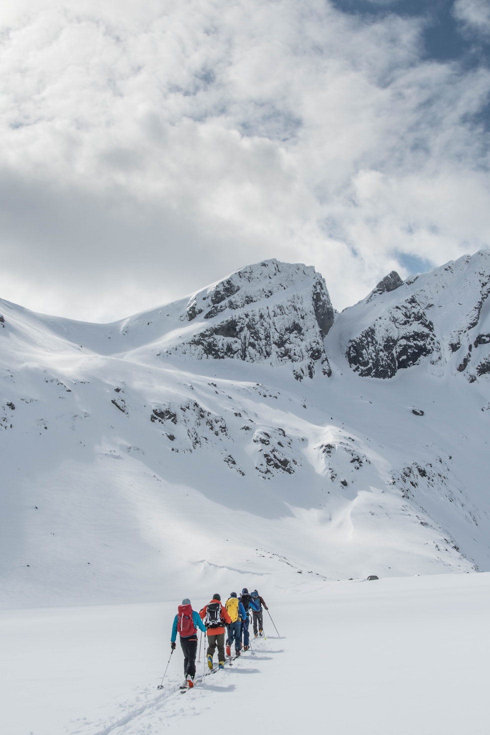 Folk på topptur på ski med fjel i sikte