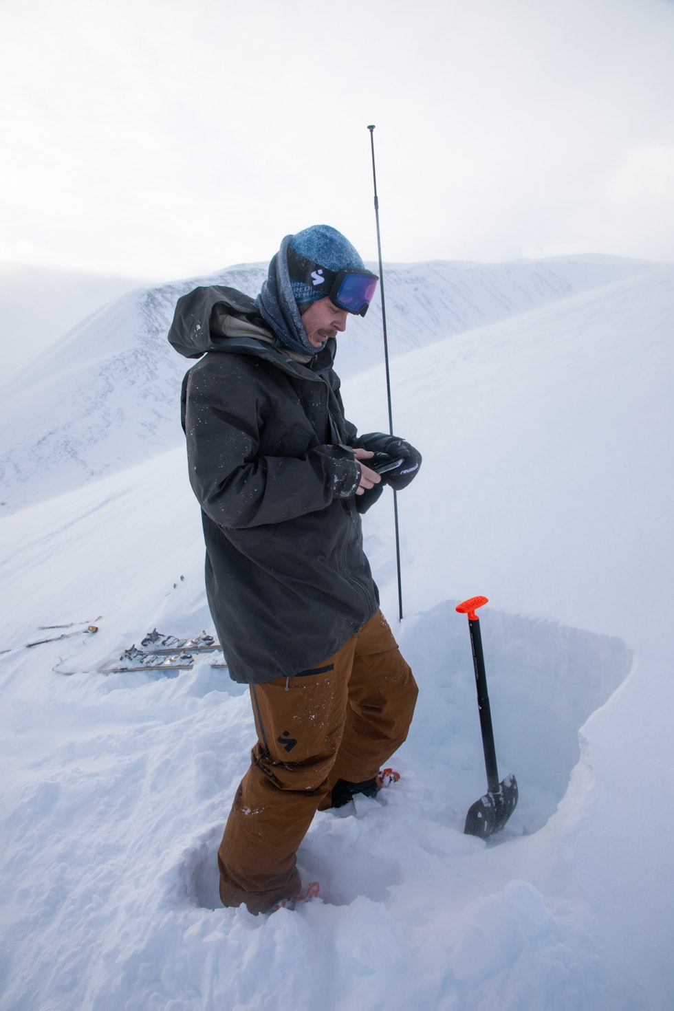 OBS: Informasjonen legges inn med appen regobs. Denne prosessen er lik enten du er fast skredobservatør eller ikke. Foto: Tore Meirik Mann med telefon i vinterfjellet